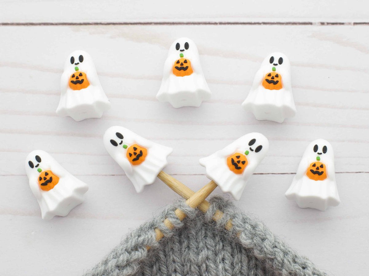 Halloween-themed ghost stitch stoppers on knitting needles