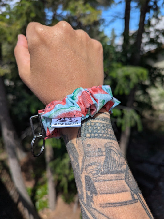 Hand wearing a colorful scrunchie with a blurred natural background