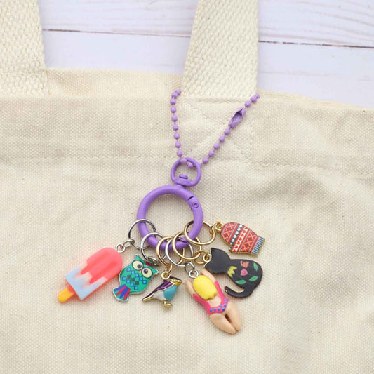Keychain with colorful charms attached to a beige tote bag.