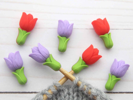 Colorful tulip-shaped stitch stoppers on knitting needles