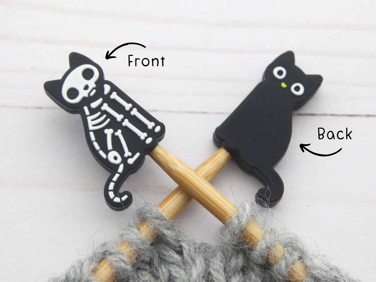 Two black cat-shaped stitch stoppers on knitting needles