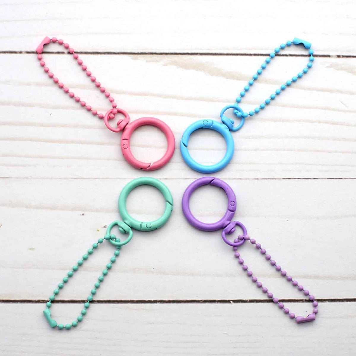 Four colorful keychains with rings on a wooden surface