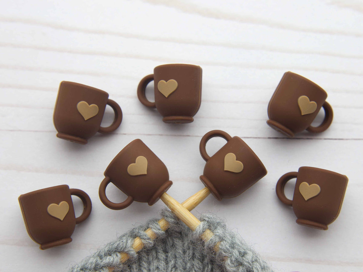 Chocolate mugs with heart shapes , stitch stoppers on a white wooden surface