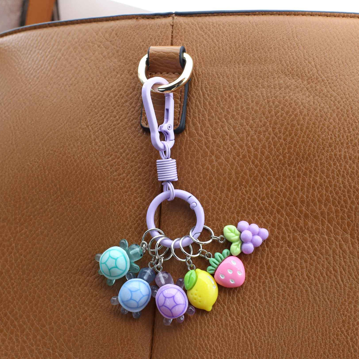 Colorful keychain with charms attached to a brown leather bag
