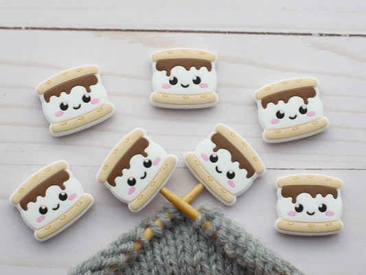 S'mores cookies stitch stoppers with cute faces on a wooden surface