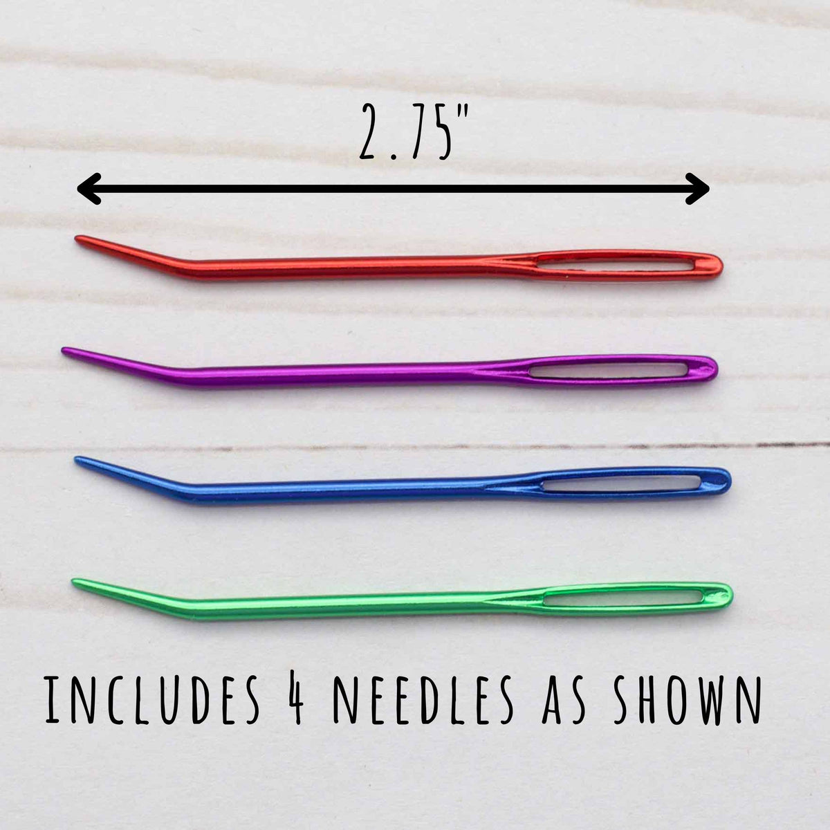 Set of four colorful needles with a measurement label on a light wooden background