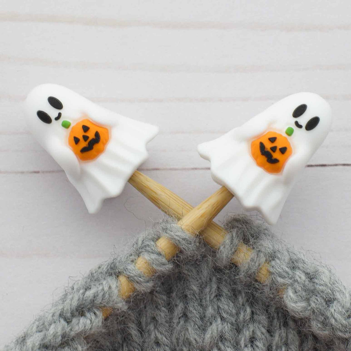 Ghost stitch stoppers on knitting needles