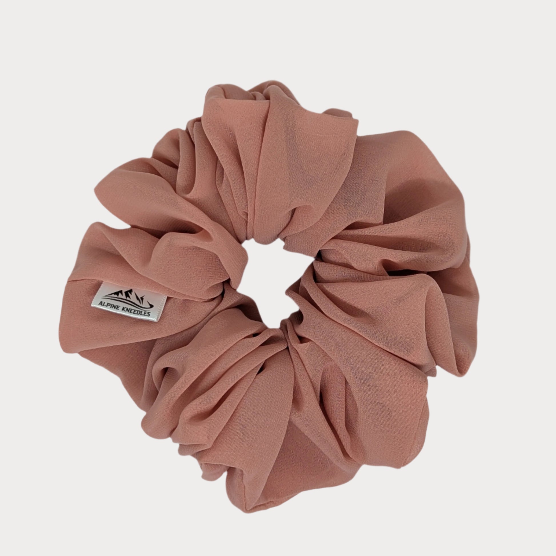 Pink scrunchie with a brand label on a white background