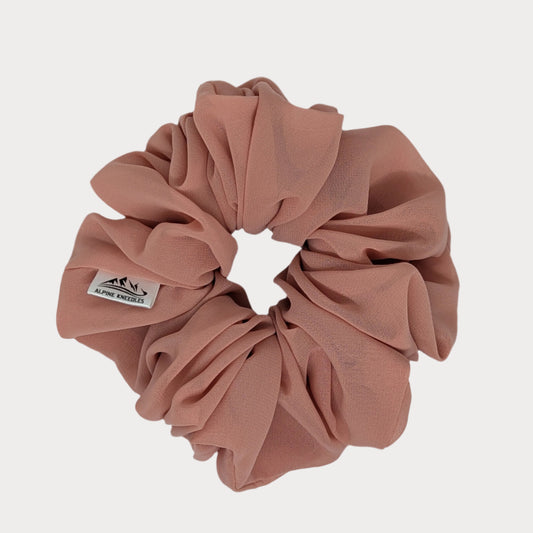 Pink scrunchie with a brand label on a white background