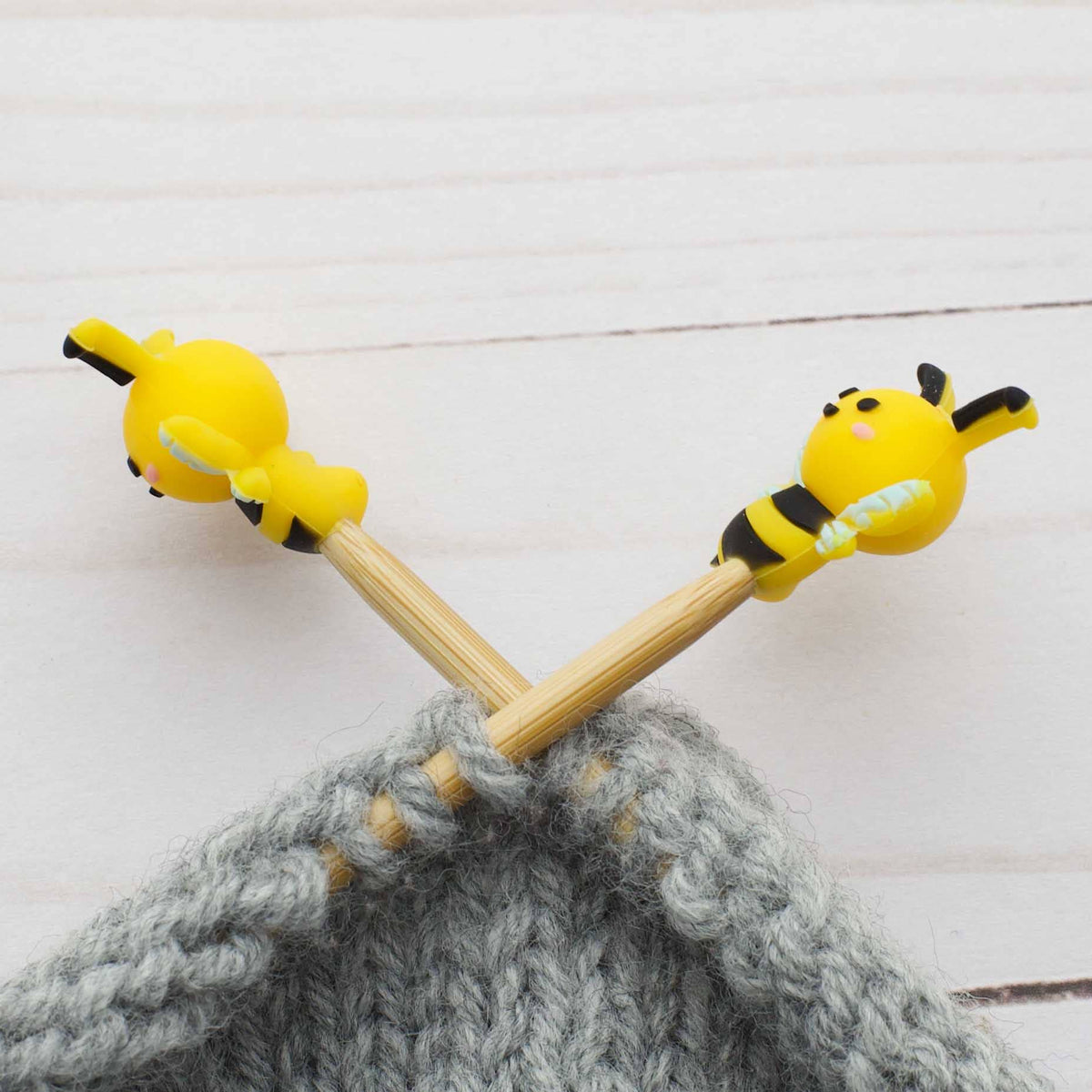 Bee side view of stitch stoppers on knitting needles