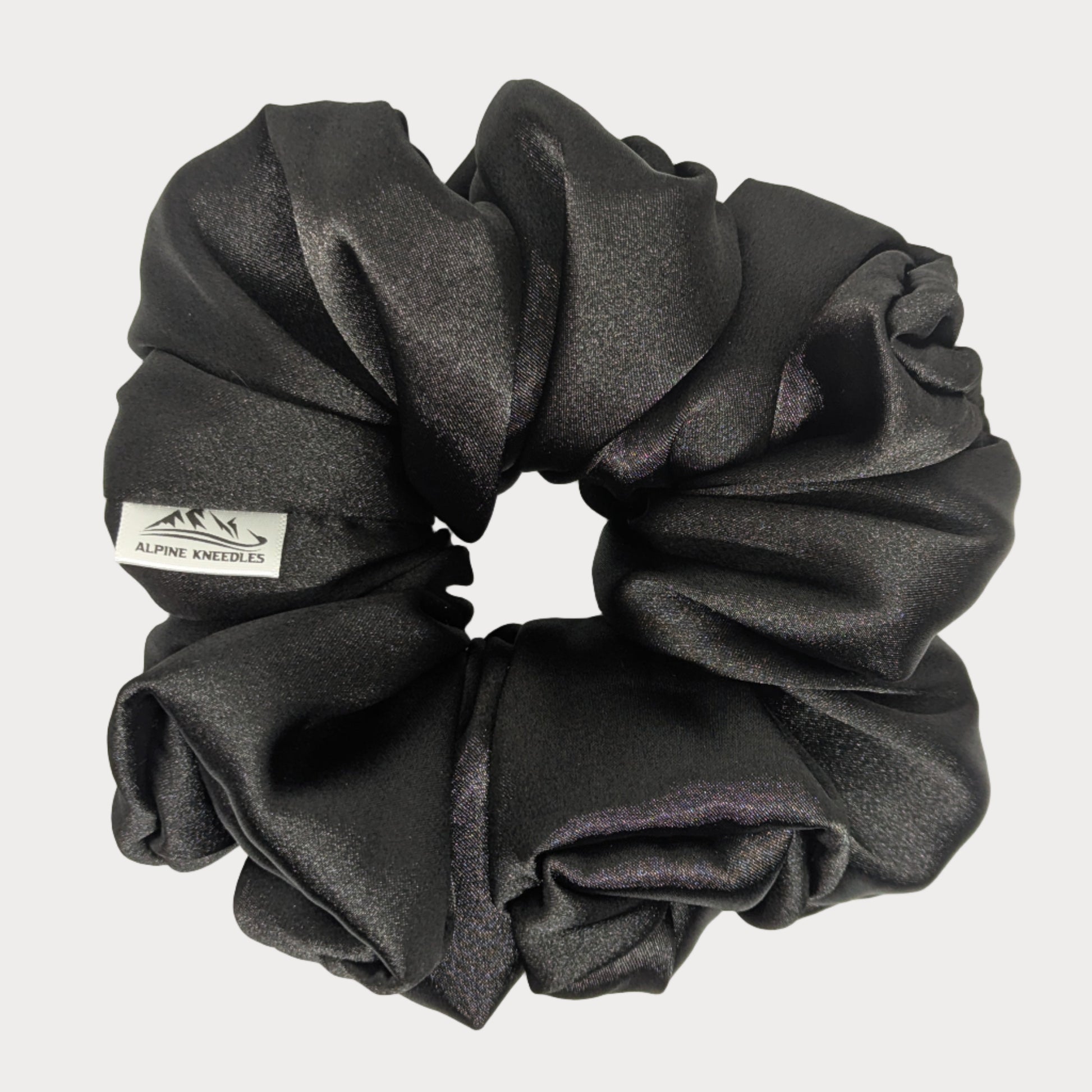 Black scrunchie with a brand label on a white background