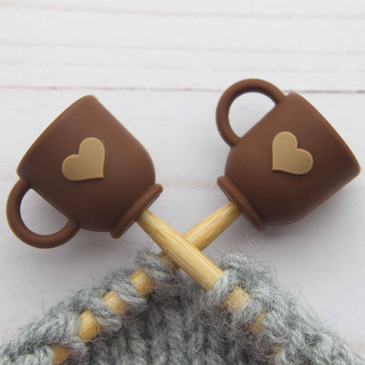 Brown mug stitch stoppers on knitting needles