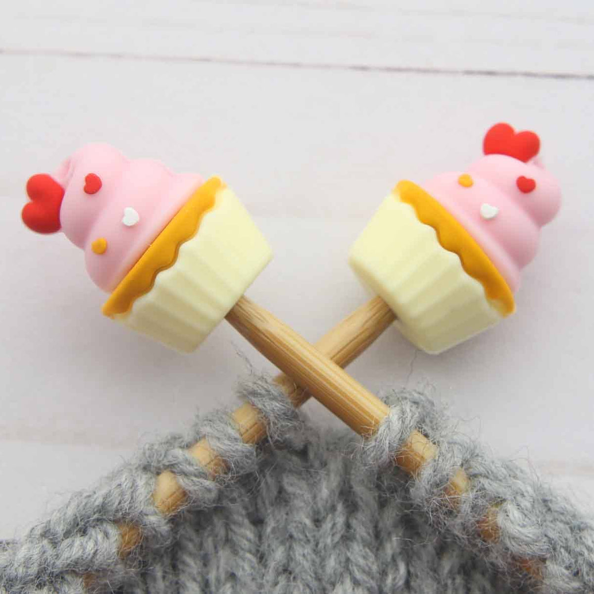 Cupcake-shaped stitch stoppers on knitting needles