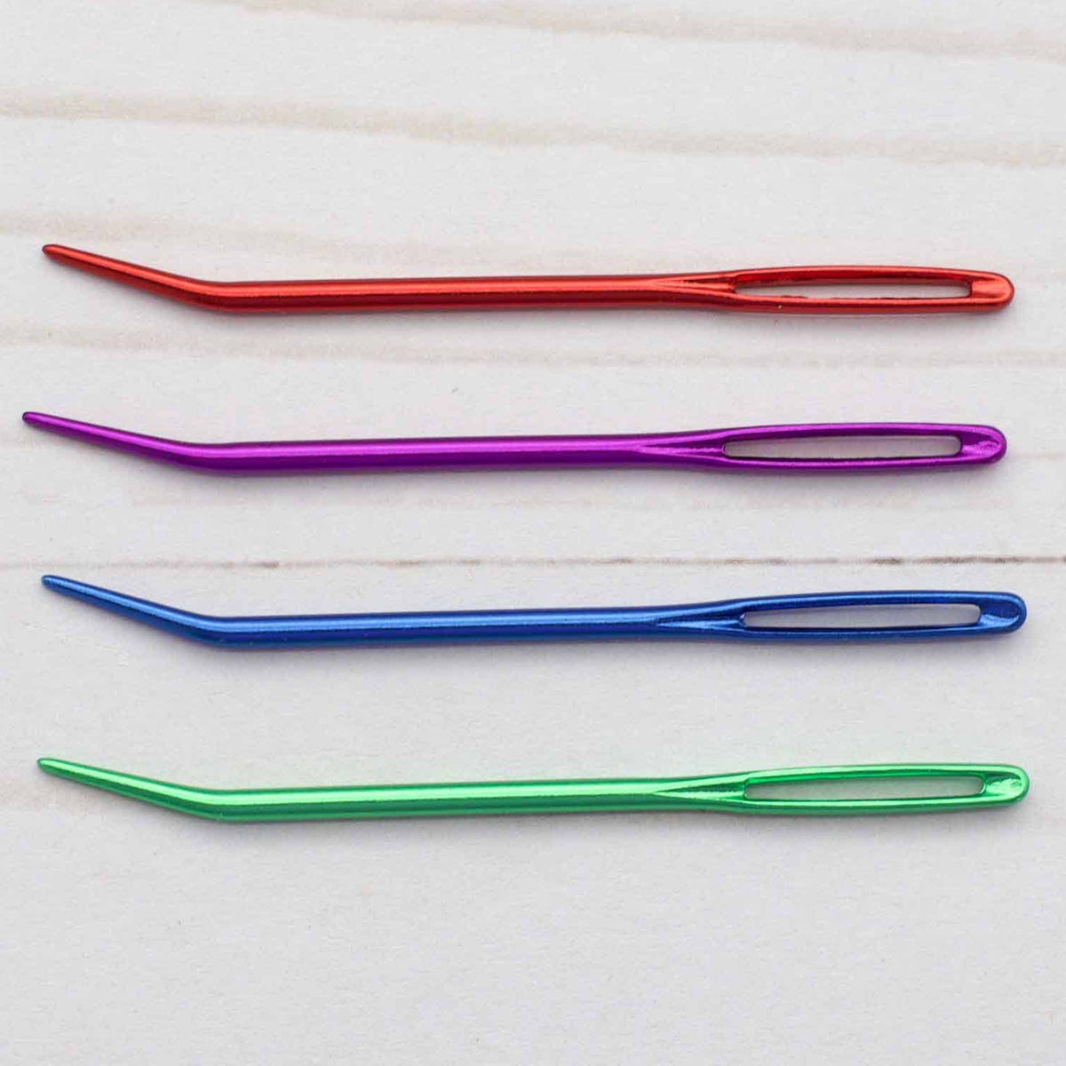 Four colorful needles on a light wooden surface