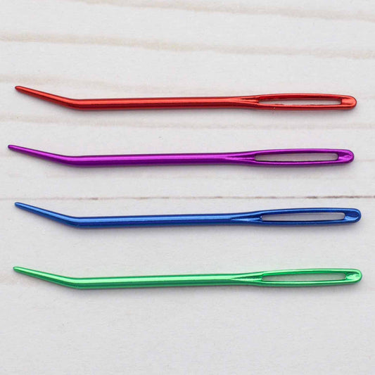 Four colorful needles on a light wooden surface