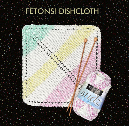 Knitted dishcloth with gradient colors, knitting needles, and a ball of yarn on a black background.