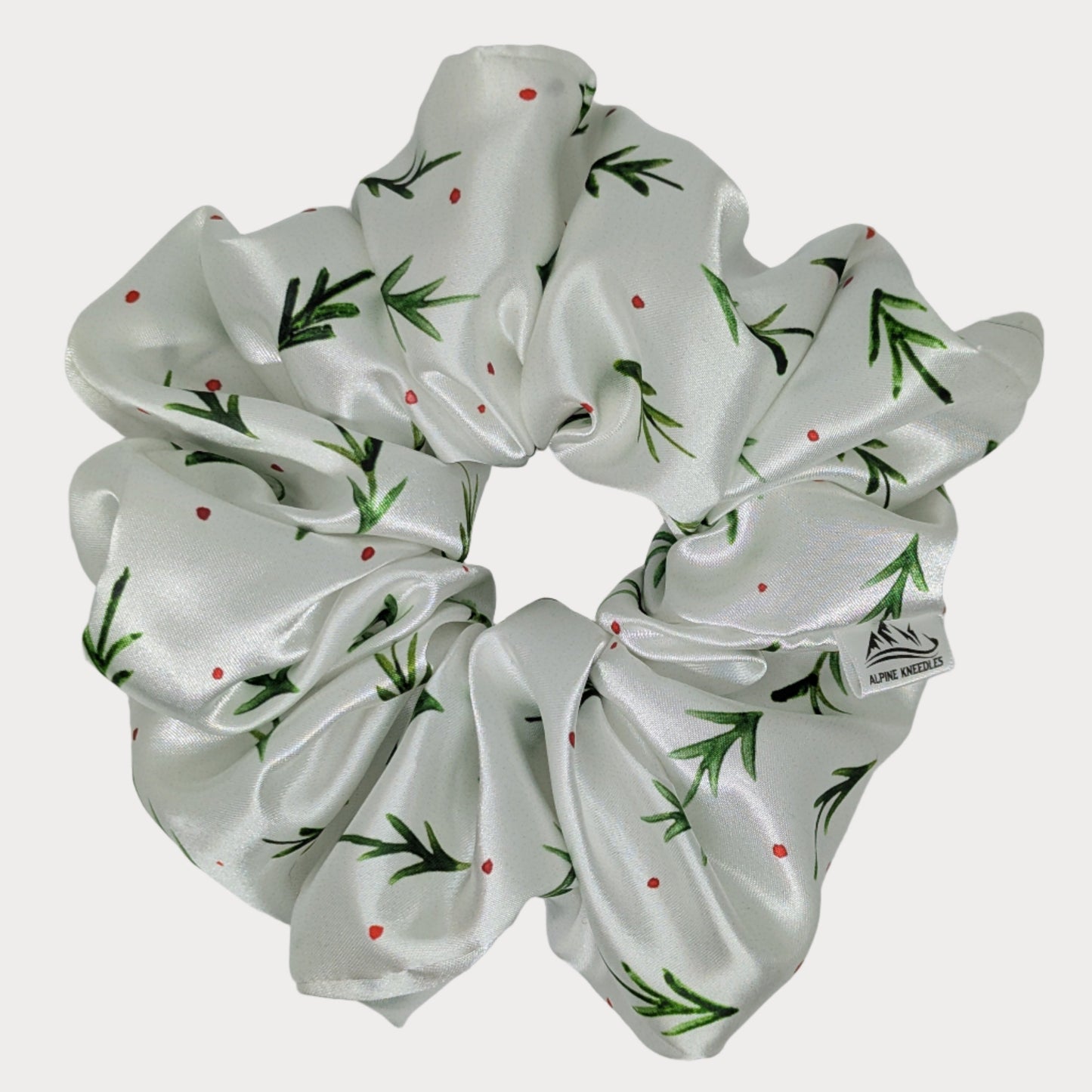 White scrunchie with green pine pattern on a gray background