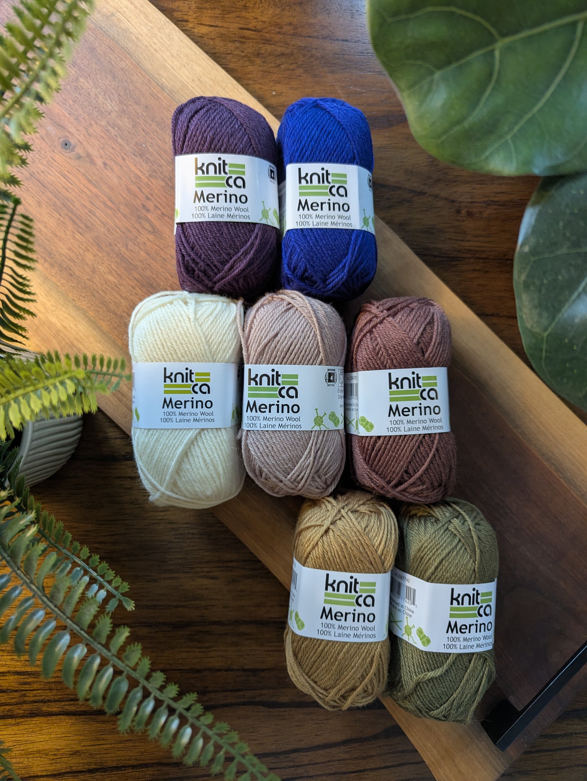 Knitca Merino yarn balls on a wooden surface with plants around