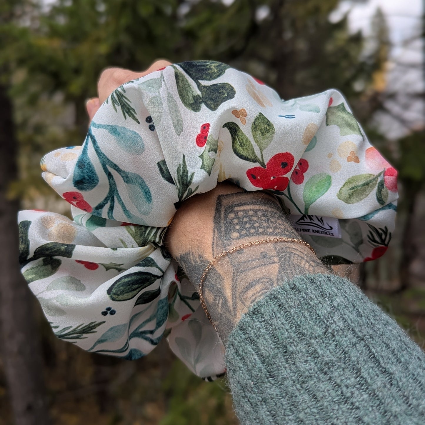 Hand holding a floral scrunchie with a forest background