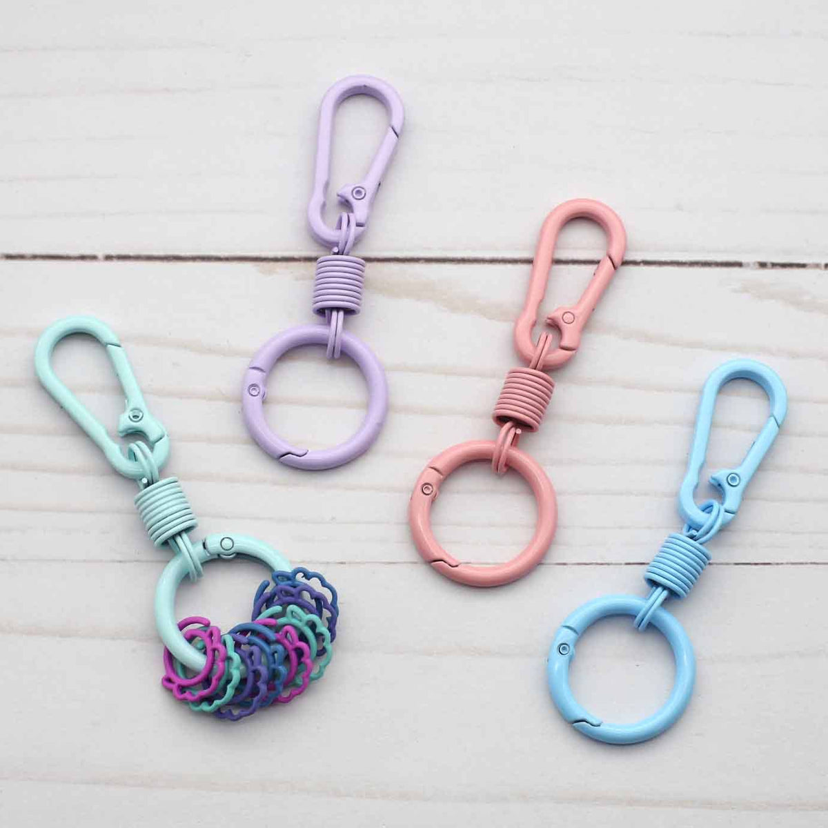 Four colorful keychains with stitch markers on a light wooden surface