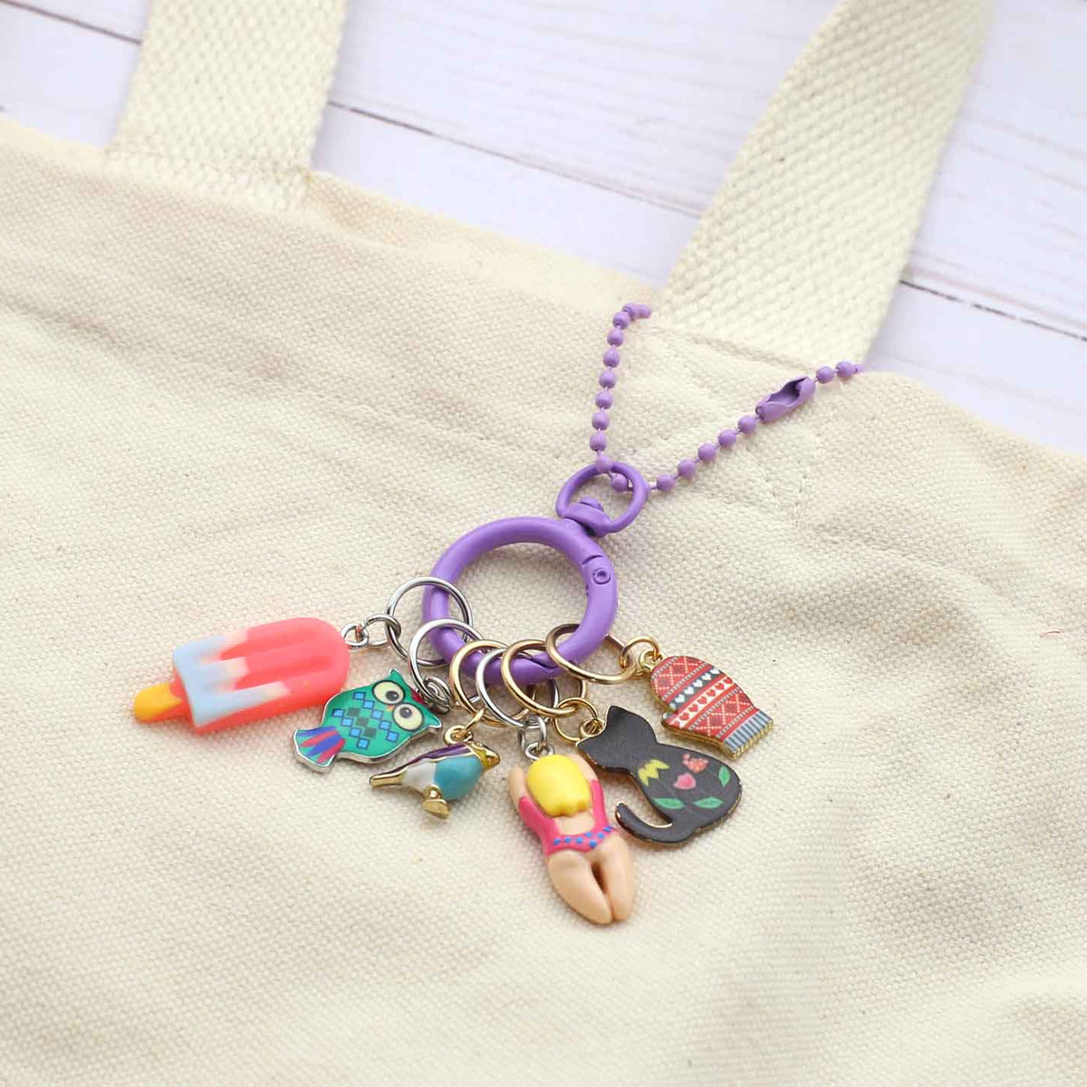 Colorful keychain with various charms attached to a beige bag.