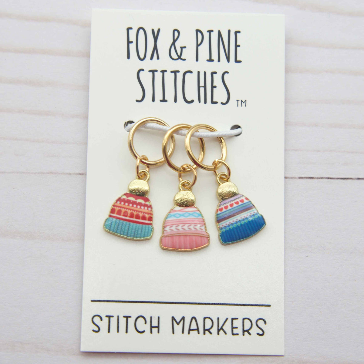 Three colorful stitch markers on a card with 'Fox & Pine Stitches' branding.